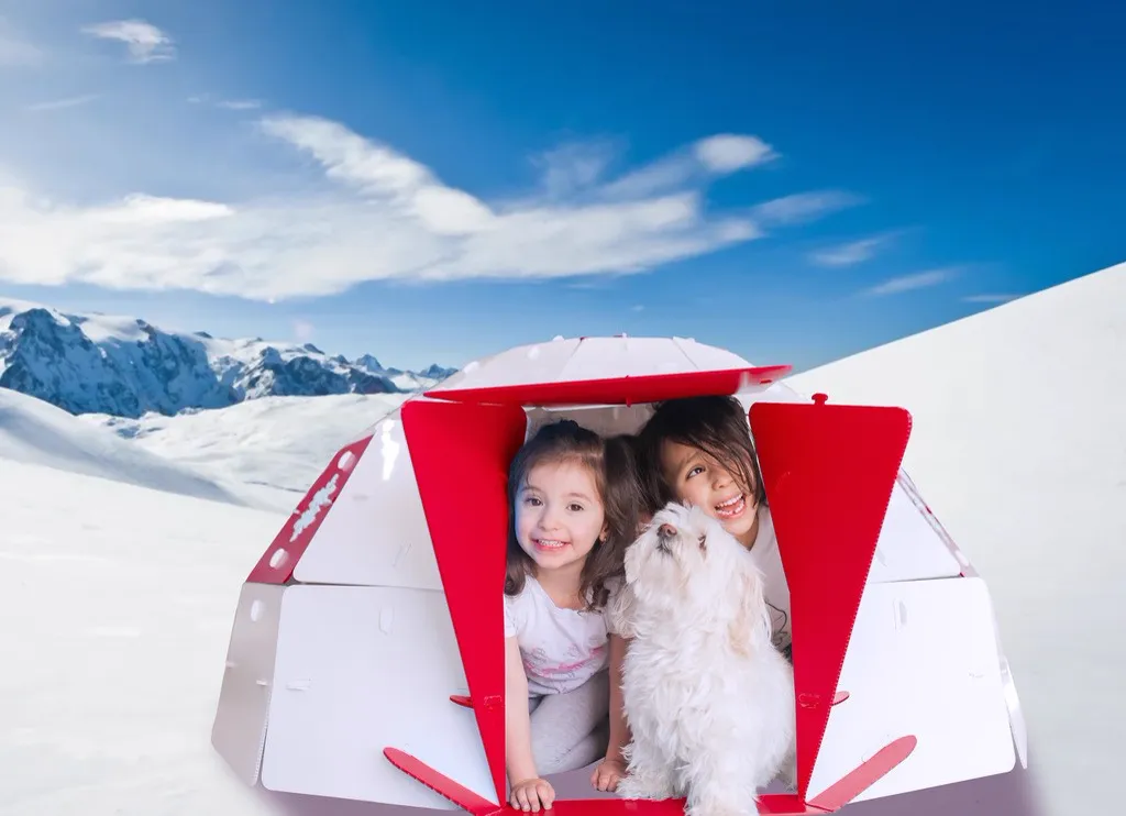 Two children and a small dog sitting inside a NimoPlay igloo playhouse in the snow