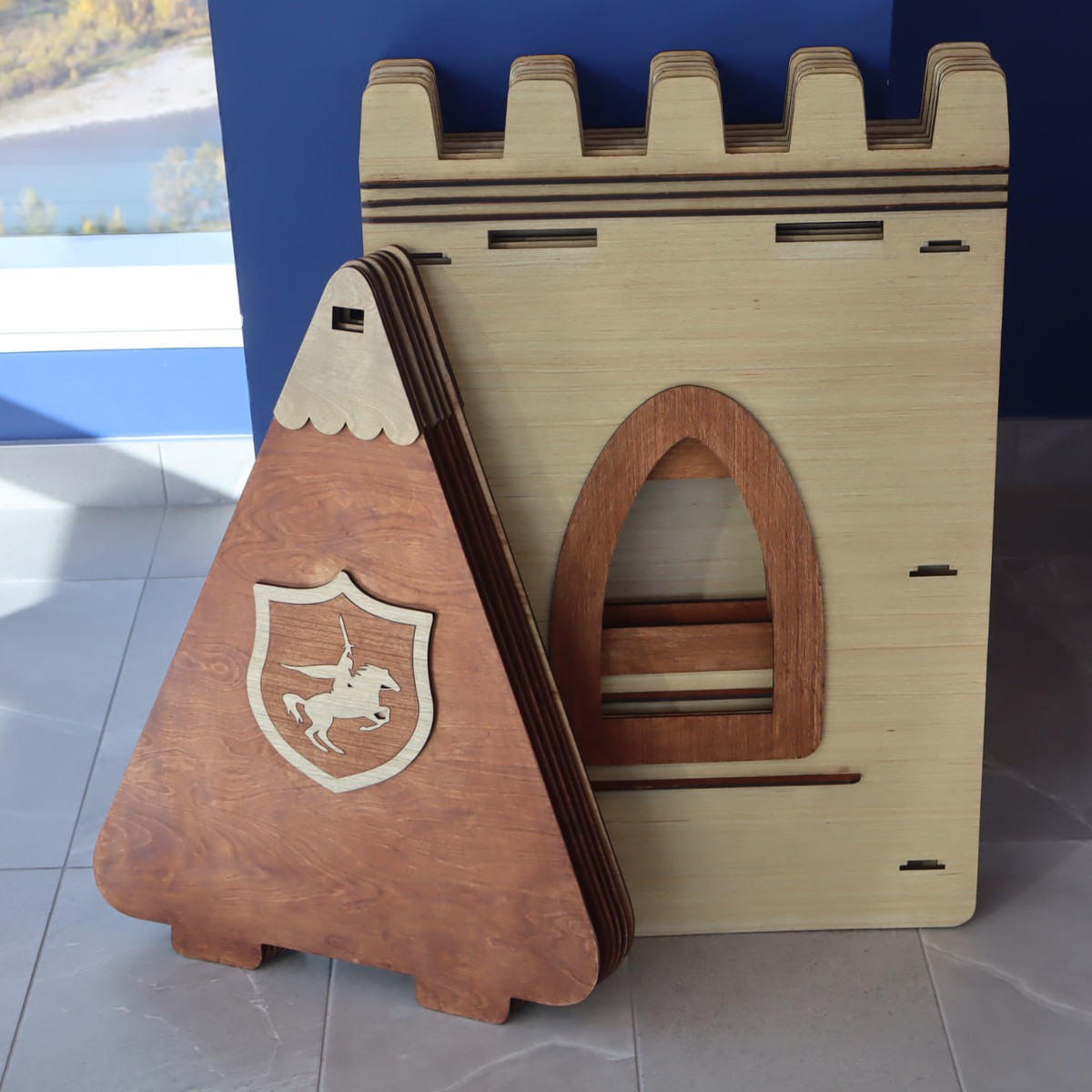A brown and natural wood NimoPlay castle playhouse packed flat against a wall
