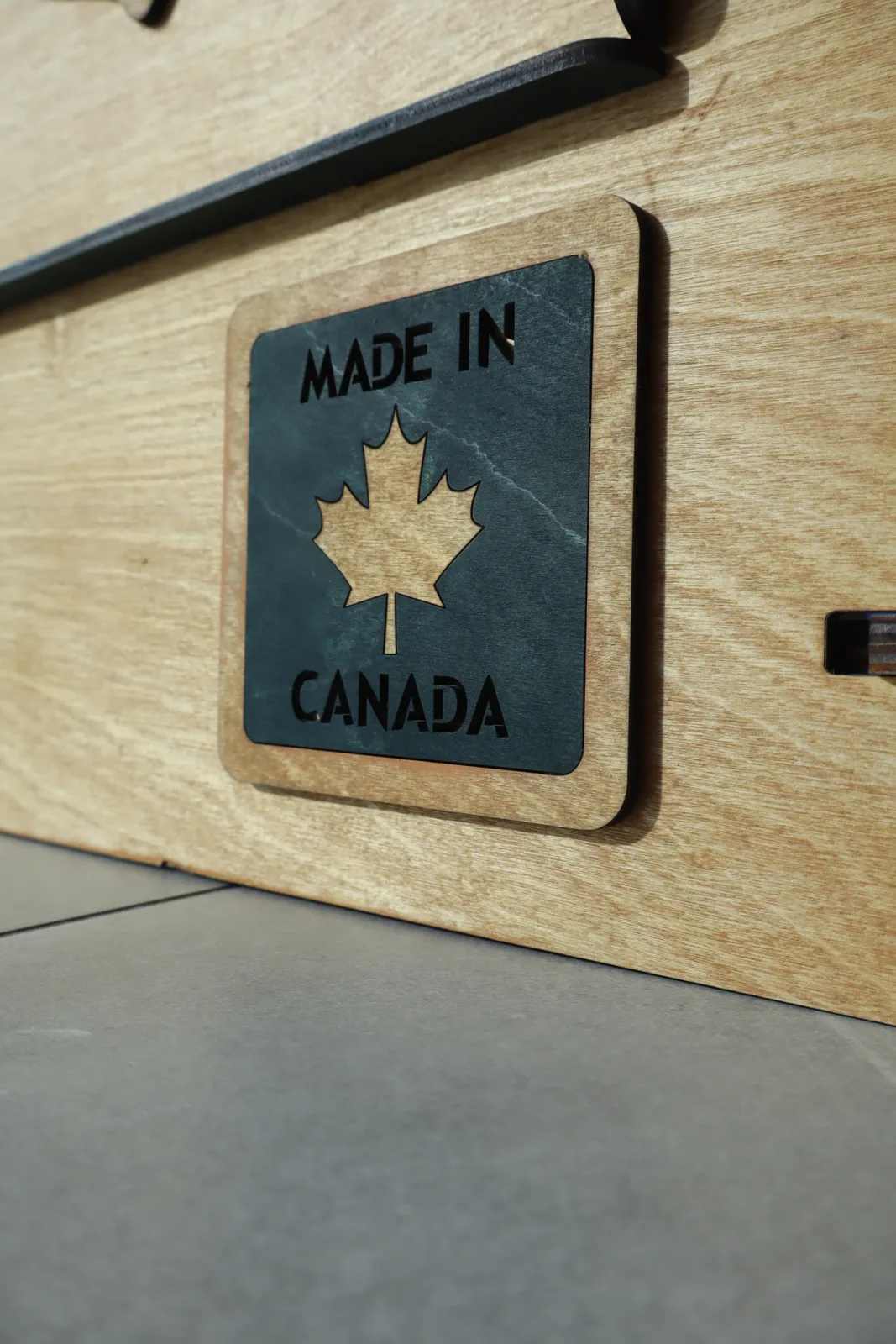 Green Made in Canada maple leaf badge on a wooden NimoPlay castle panel
