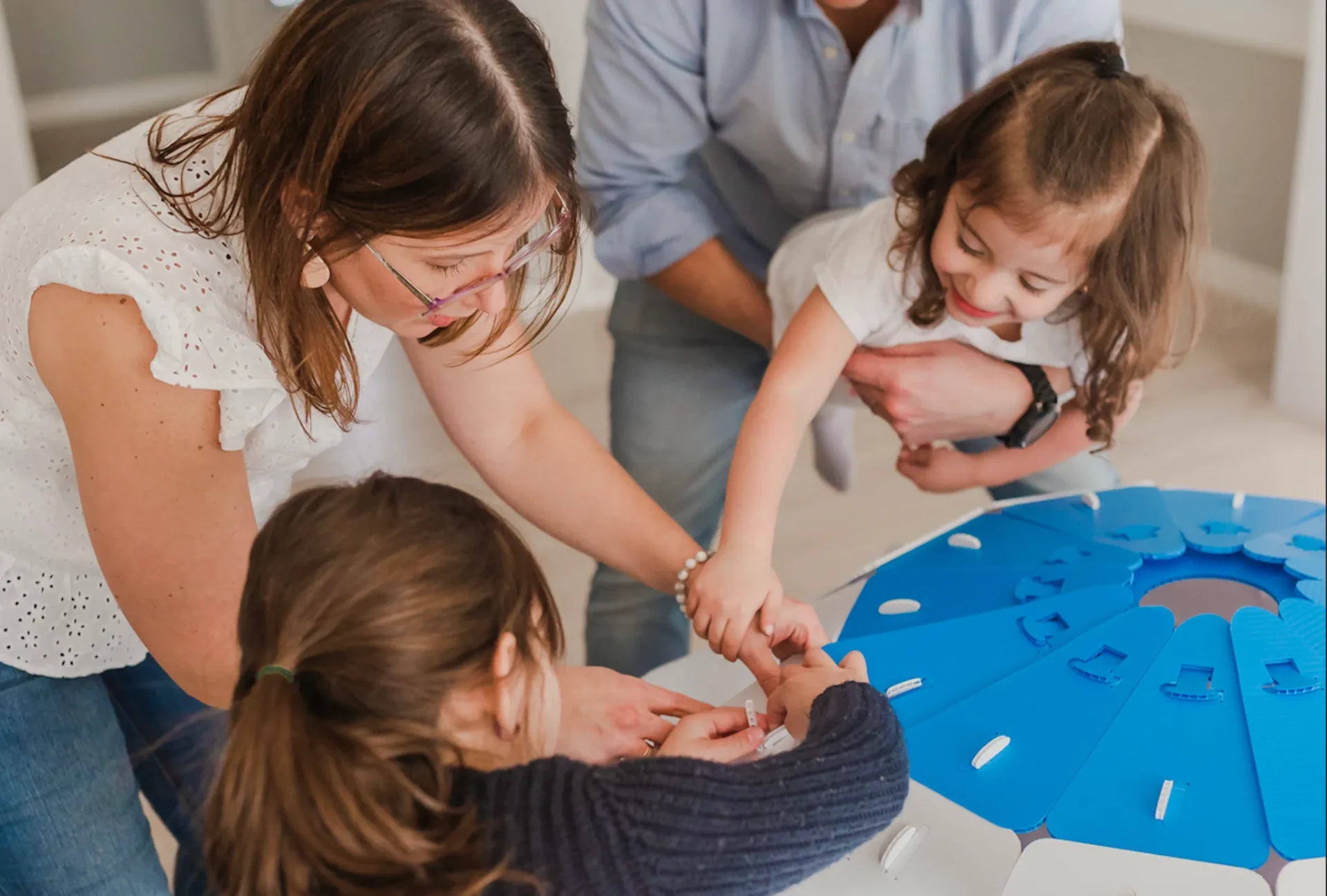 Parents and children fitting the blue roof panels of a NimoPlay igloo together
