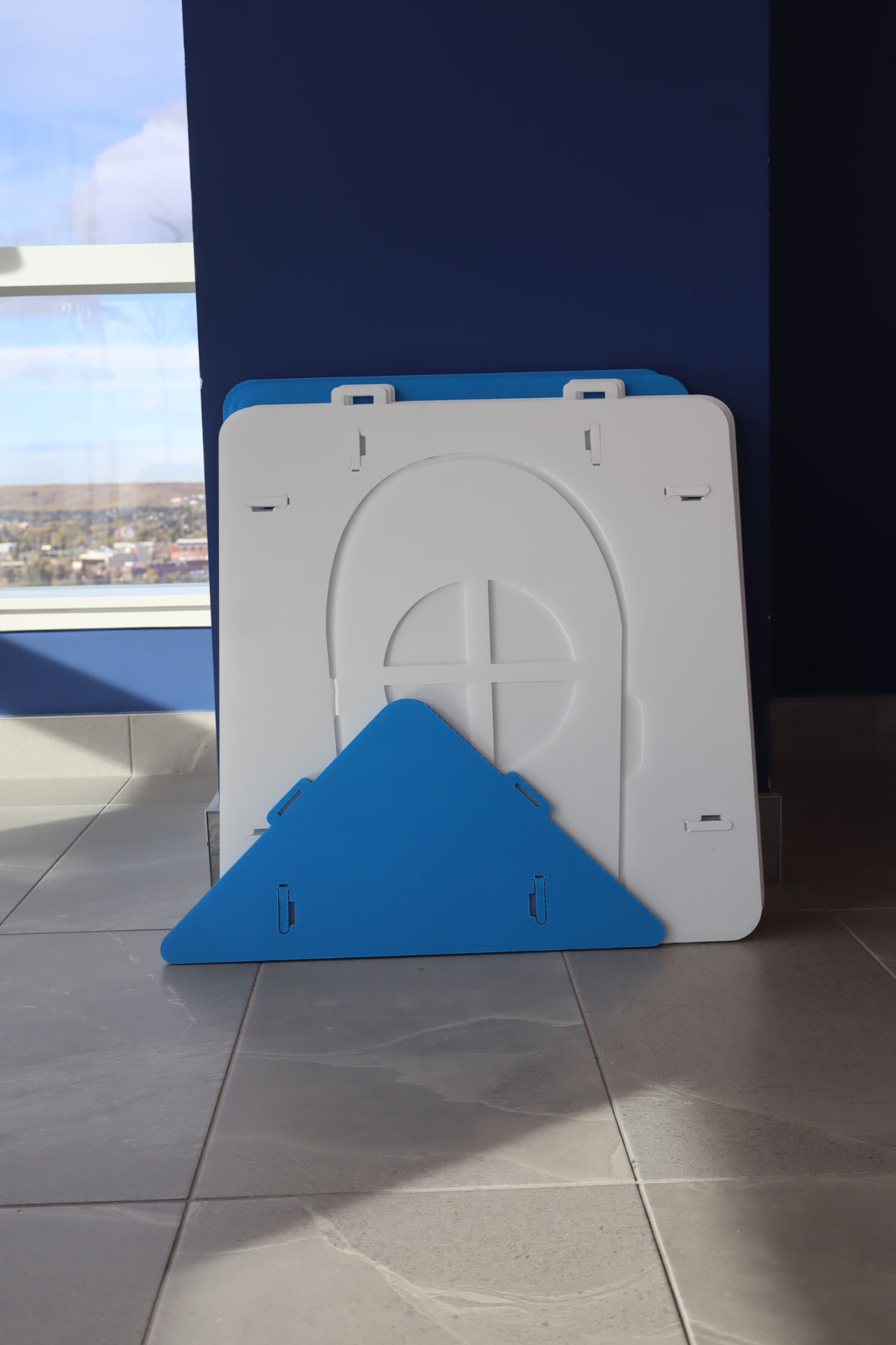 Blue and white NimoPlay igloo panels and roof pieces packed flat, leaning against a wall