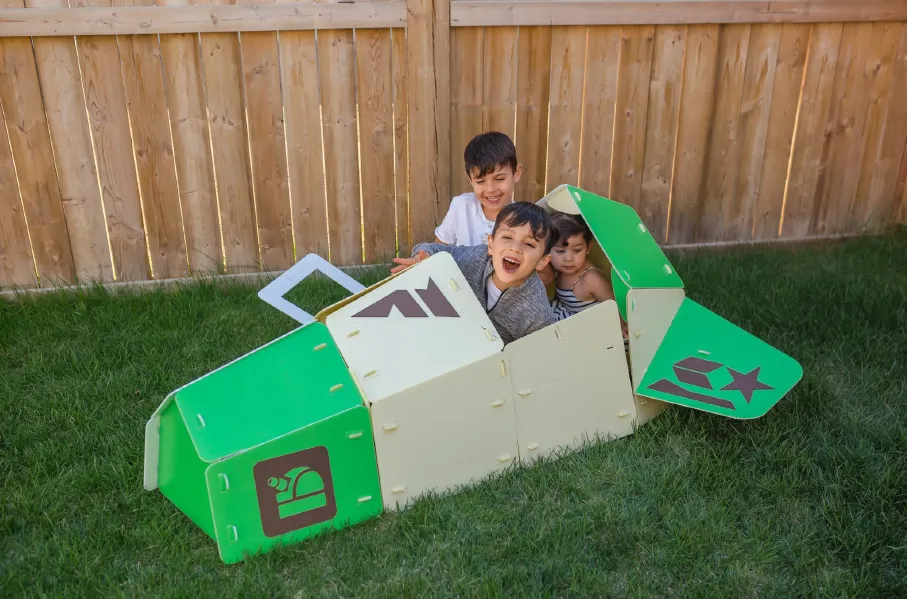 Three children imagining an adventure in a green and white NimoPlay airplane